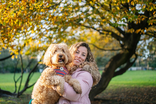 Woman holding adorable dog in autumn park