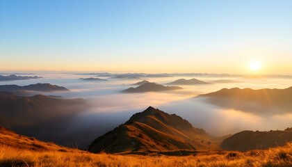 Fototapeta premium Sunrise over misty mountain range with golden grassy slopes, blue sky, and distant peaks fading into the horizon.
