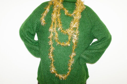 Person with green wool sweater holding golden sparkly Christmas ribbon