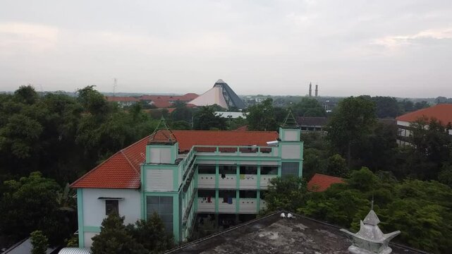 Pemandangan asrama serta bangunan berbentuk segitiga dengan nuansa awan mendung