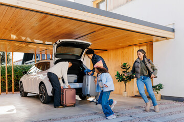 Happy family packing car for road trip vacation