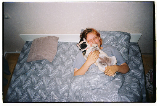 Girl cuddling with pug in cozy bedroom
