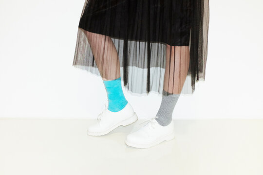 Person with fashion style skirt and different pair of socks and shoes