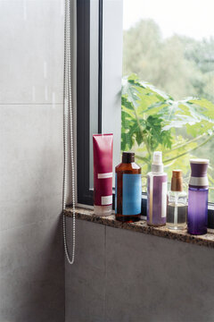 Different skin and haircare products lined up on a windowsill 