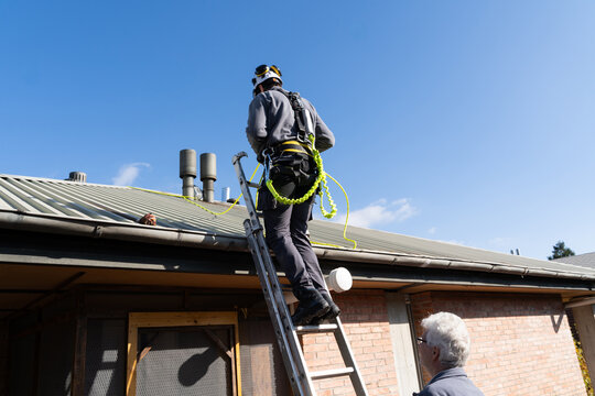 Worker Securing Rooftop Safety Harness