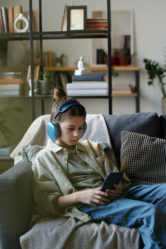 Teenage Boy in Headset Watching Music Videos on Phone at Home