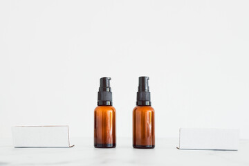 apothecary amber style moisturizer bottles next to blank labels with copy space on minimalistic white marble