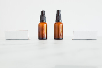 apothecary amber style moisturizer bottles next to blank labels with copy space on minimalistic white marble
