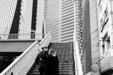 Couple ascending stairs surrounded by urban skyscrapers