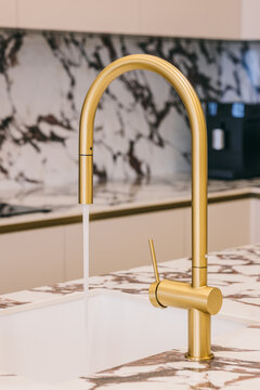 Modern gold kitchen faucet with marble countertop background