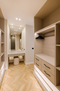 Modern walk-in wardrobe with elegant beige finishes and lighting