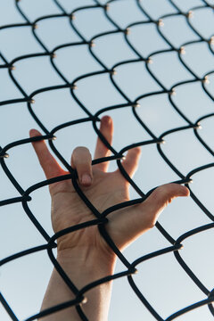 Hand gripping chain-link fence