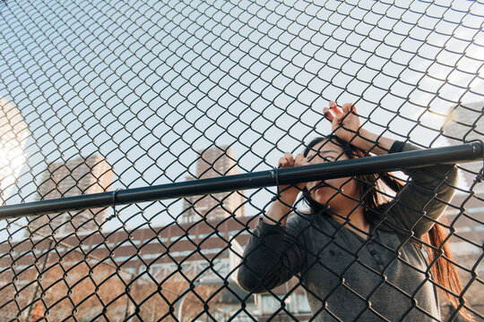 Woman peering through chain-link fence