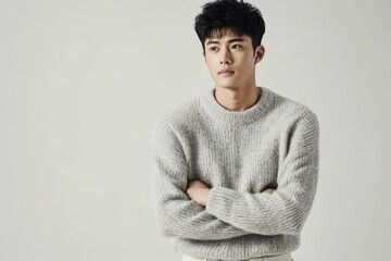 A young Chinese man, wearing a light grey sweater and off-white chinos, natural skin tone, short black hair, with a thoughtful and approachable expression, 