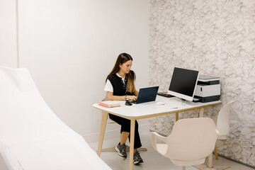 Dermatologist working with a laptop at her desk inside her office
