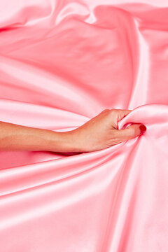 Crop female hand grabbing silk