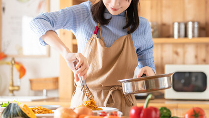 キッチンで料理をする女性（パスタを盛り付ける）