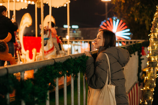Woman admiring a festive carousel during holiday evening