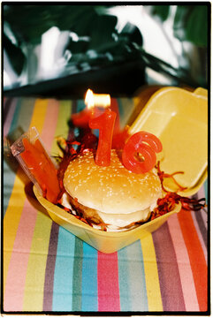 motion blur of a burger topped with lit 16 number-shaped candles, 35mm