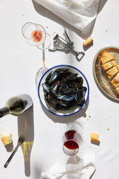 Flat lay of mussels, bread, and wine on a white tablecloth