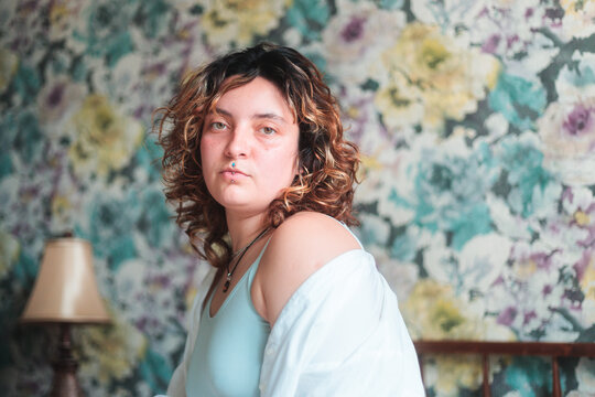Young woman in bedroom with floral wallpaper