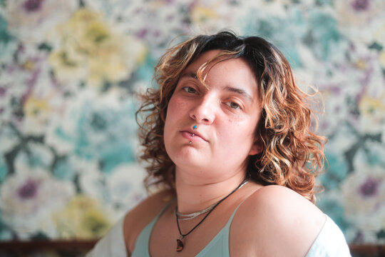 Latina woman looking at camera in front of floral wallpaper