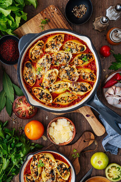 Baked stuffed pasta shells in tomato sauce with fresh garnishes.