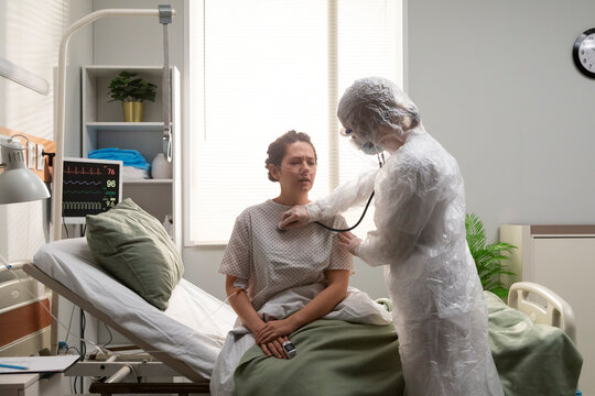 Doctor wearing ppe suit examining patient with stethoscope 
