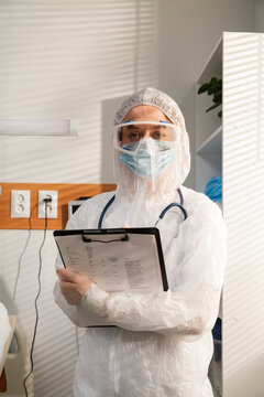 Doctor wearing protective suit holding medical record 