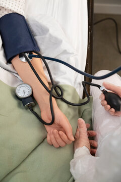 Doctor measuring blood pressure of patient in hospital bed