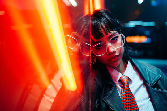 Cool woman leaning on neon sign in urban setting at night