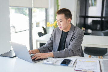 Naklejka premium Asian Business man working with laptop. Young business man thinking Concentrated at work.