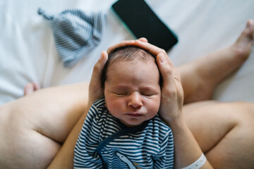 Mother holding newborn baby after cesarean section in hospital bed