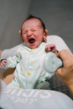Mother using soft brush on crying newborn baby after cesarean section