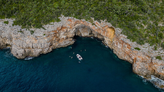 Friends Exploring a Sea Cave and Swimming by Their Boat