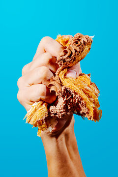 man crushing a piece of cake in his hand