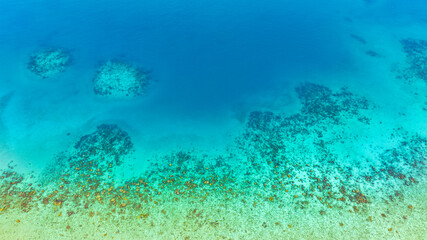 Obraz premium Top view, sandy beach background for summer vacation concept. Nature of beach and summer sea water with sunlight, sparkling sea water, coral reefs, underwater.