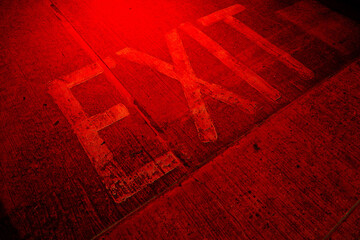 Faded "Exit" sign on pavement under red light