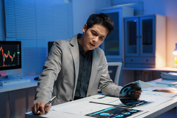 Financial analyst working late examining reports in his office