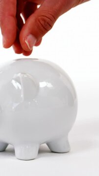 Hand inserting coin in piggy bank