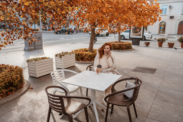 Woman Autumn Cafe Outdoor: Relaxing solo at a city cafe under autumn leaves.