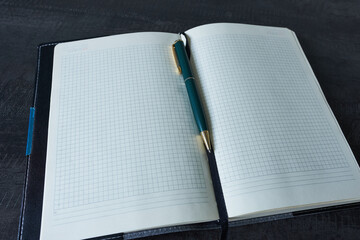 A diary and a pen on a black desk. Close-up.      