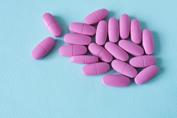 Pink pills isolated on blue background. Top view. Copy space.