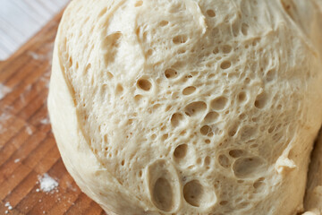 Close up of raw dough on a wooden cutting board with flour.