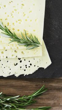 Variety of cheese, olives, biscuits and rosemary herbs on wooden table