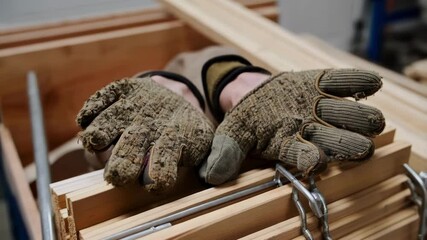 Construction gloves covered in sawdust lying on wooden drawers secured with metal clamps. Industrial workplace safety equipment in carpentry workshop