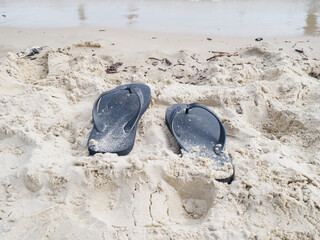 black flip flops on beach sand. summer concept