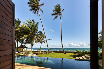 Vintage tropical villa with pool and ocean view. Palm trees sway in coastal breeze. Peaceful retreat destination for travel, relaxation, luxury lifestyle.
