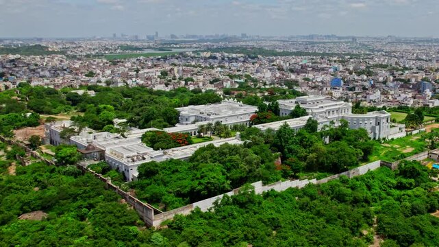 Aerial view of taj falaknuma palace with greenery and crowded residence buildings at engine bowli, falaknuma, hyderabad, telangana, india. day time, semi orbit shot, drone shot, 4k.