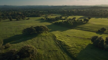 Obraz premium Aerial View of Serene Rolling Hills and Lush Green Pastures at Sunset